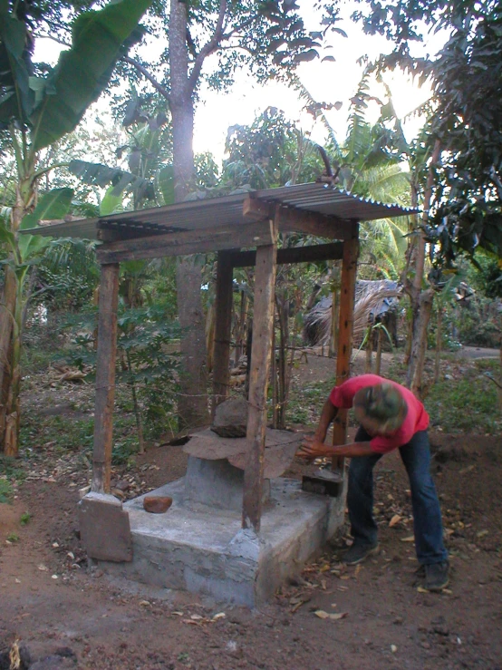 a man standing over a stone platform and putting up a piece of wood