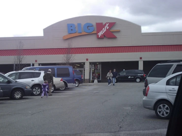 the outside of a big k grocery store with some parked cars