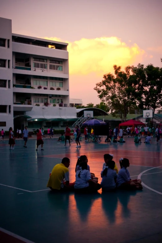 the sun is going down in the city with people on the court