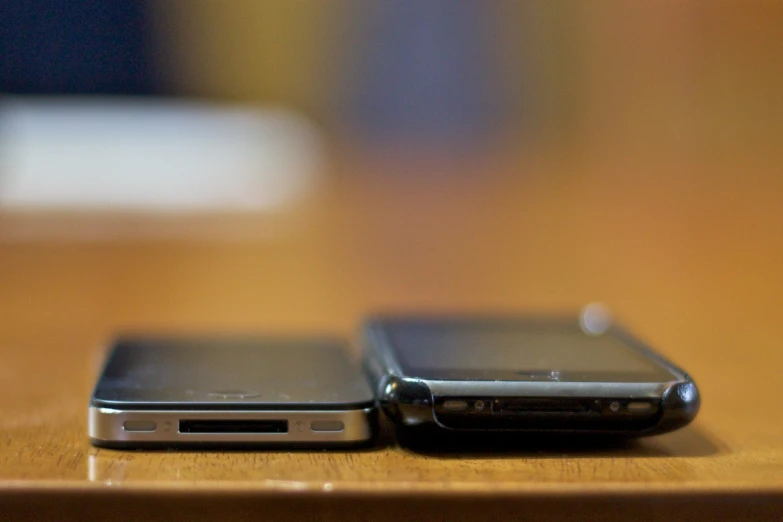 two black phones sitting next to each other on top of a wooden table