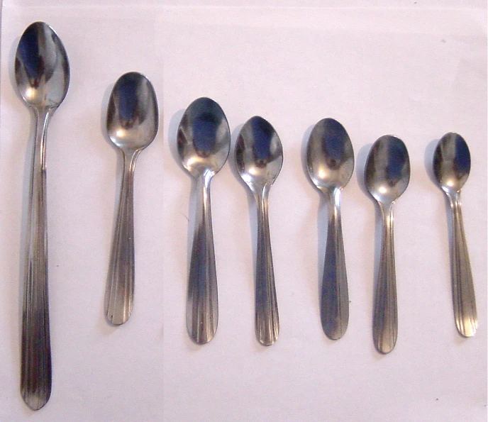 six spoons of various styles on a white table