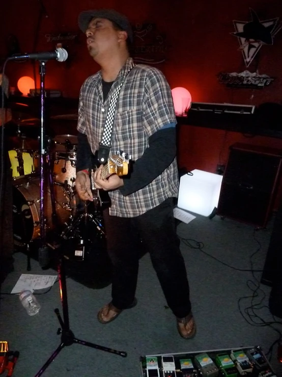 a man is singing into his guitar while standing in front of a microphone