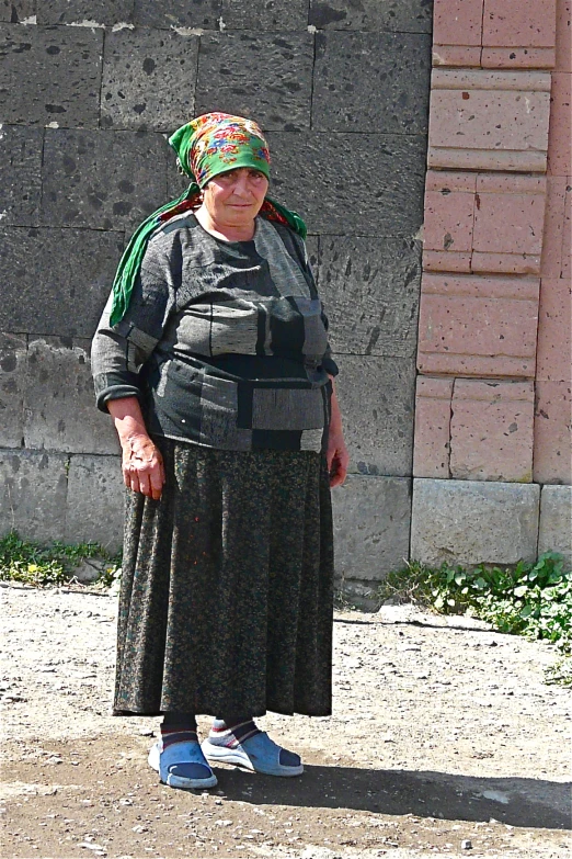 a woman standing in front of a building with a green bandanna