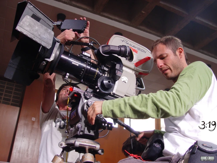 a man standing by some electronics, and another man with a camera