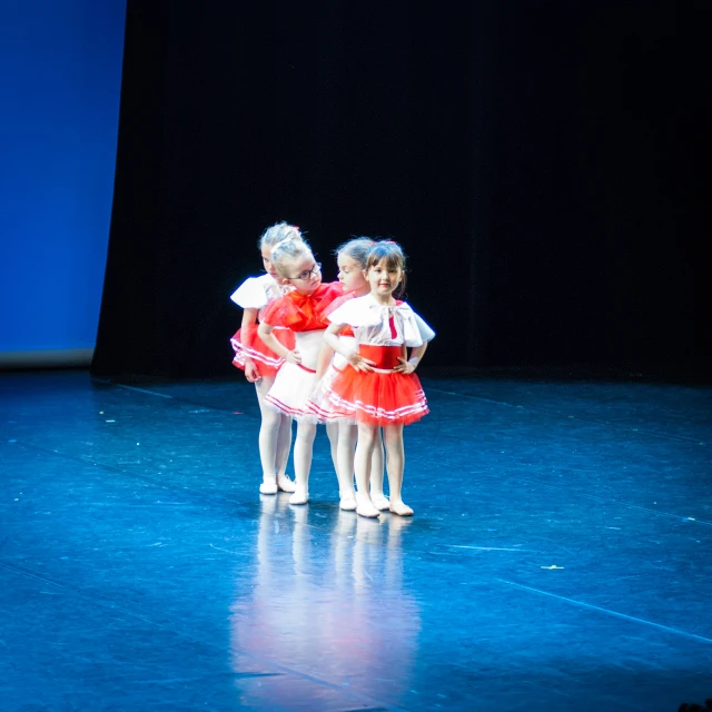 three little girls on a stage with blue light