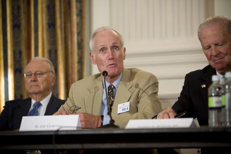 three men sitting in front of a table at a meeting