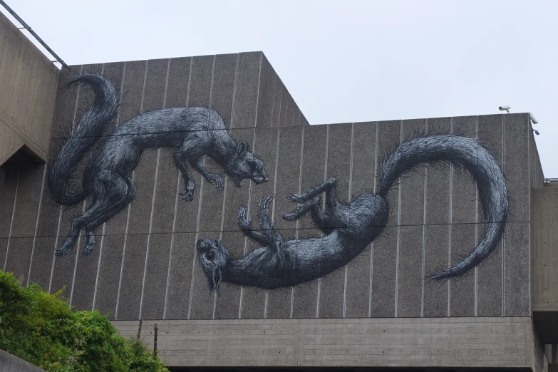 two foxes on a building, with one wolf in its mouth