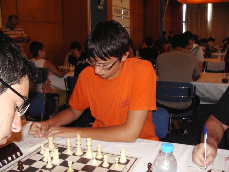 a man playing chess with another man sitting down