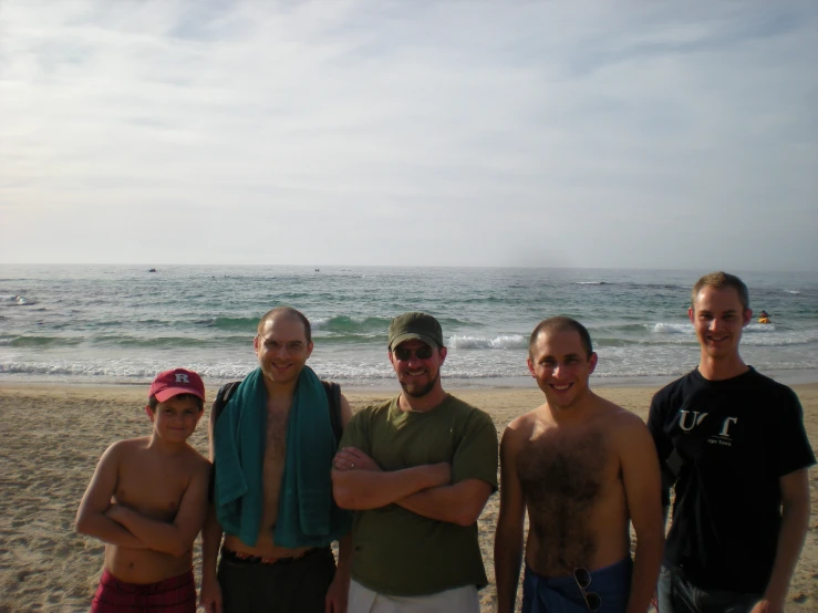 there are four men standing on the beach near the water