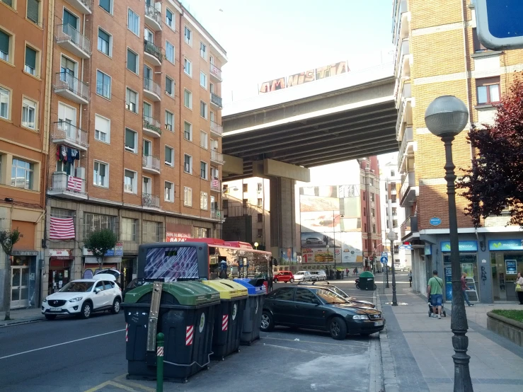 cars parked on the side of a road next to tall buildings