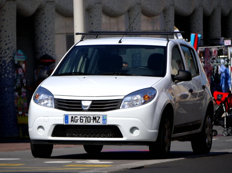 small white suv on roadway with people and buildings