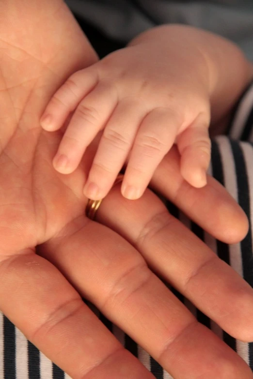 a small child's hand with a gold ring on it