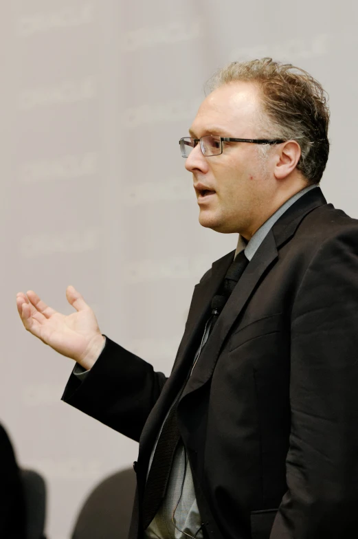 a man in black suit giving a speech