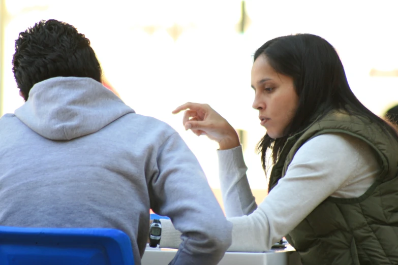 a woman looking at her cell phone while sitting at an outdoor table