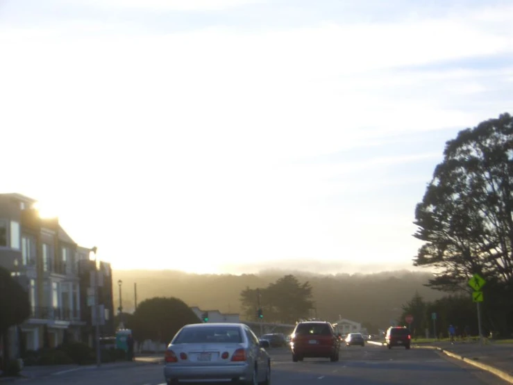 a street with several cars on it as the sun begins