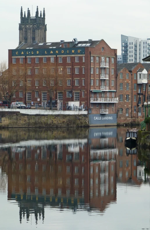 the large brick building is reflected in the lake