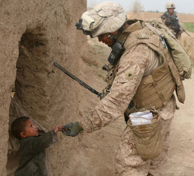 a soldier giving a child a hand on a desert
