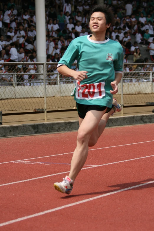 a person running on a track with people in the stands