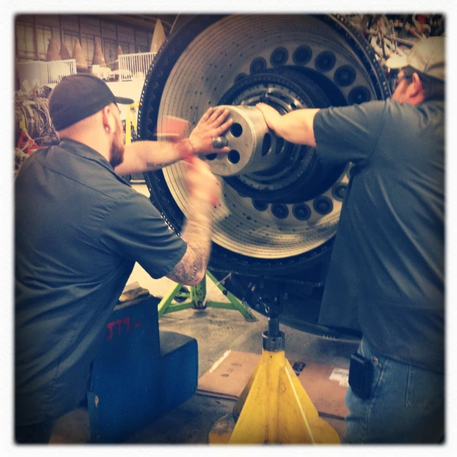 two men working on an oversized tire in a factory