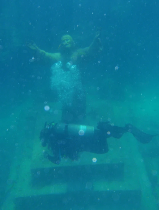 a man swims in the blue water and holds his arms up as he looks at soing