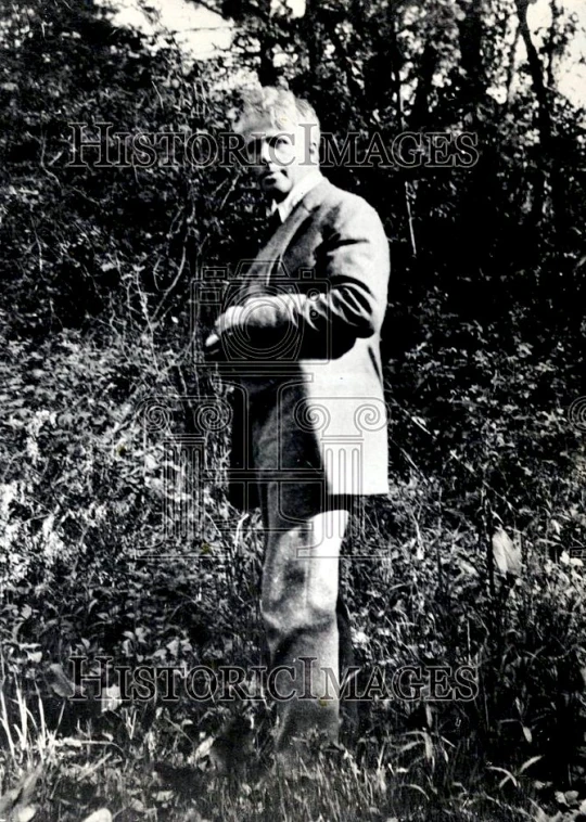a man in a suit standing next to plants