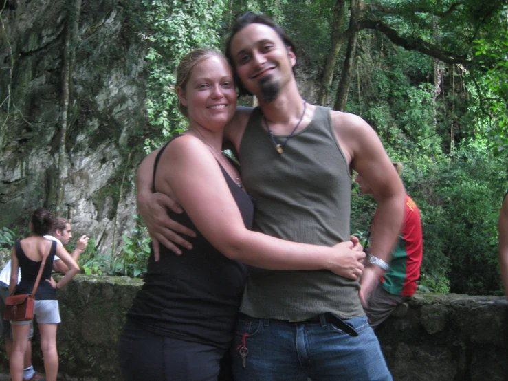 a man and woman posing for a picture in the woods