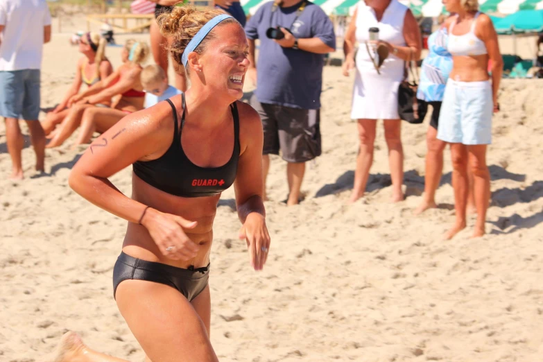 a young woman runs on a beach in her bathing suit