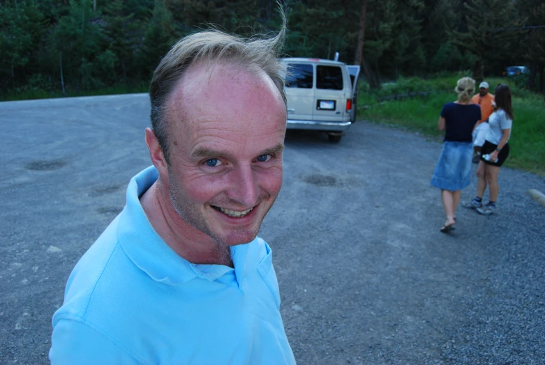 a man standing in front of an suv near two people