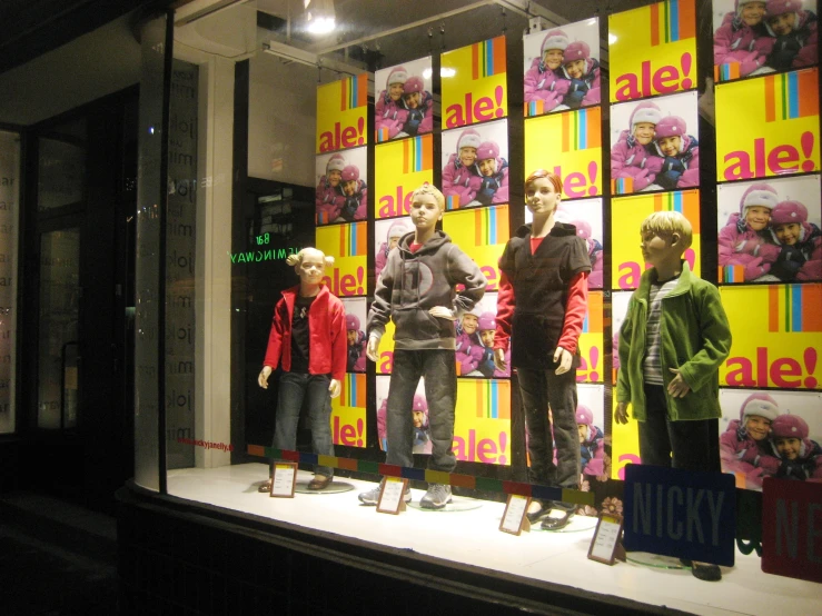 a display of dolls standing in a window with posters
