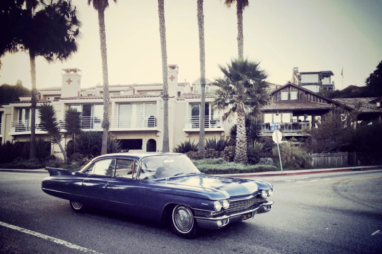 a classic car parked in front of apartment buildings