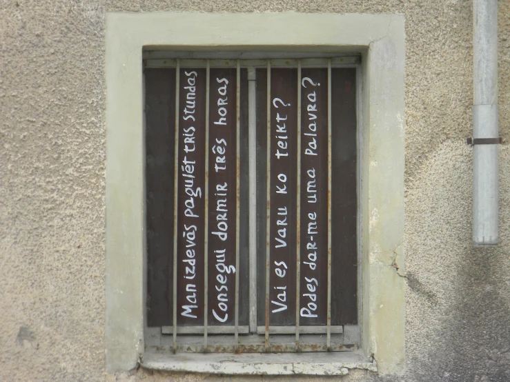 a window with an iron bars attached to it that has writing written on the glass