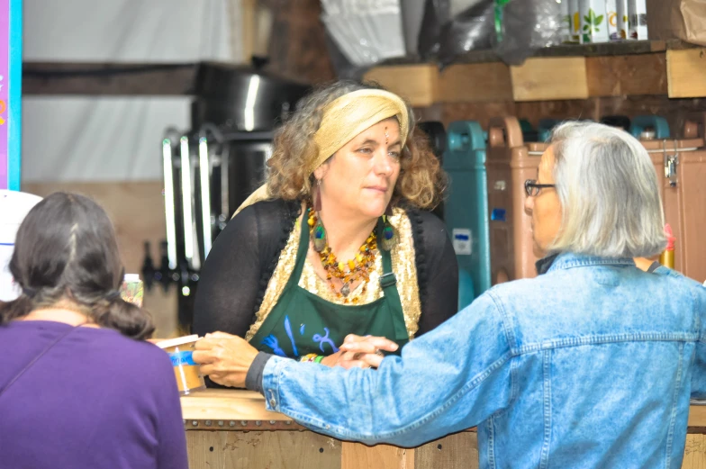 a woman at the counter of a shop talking to another woman