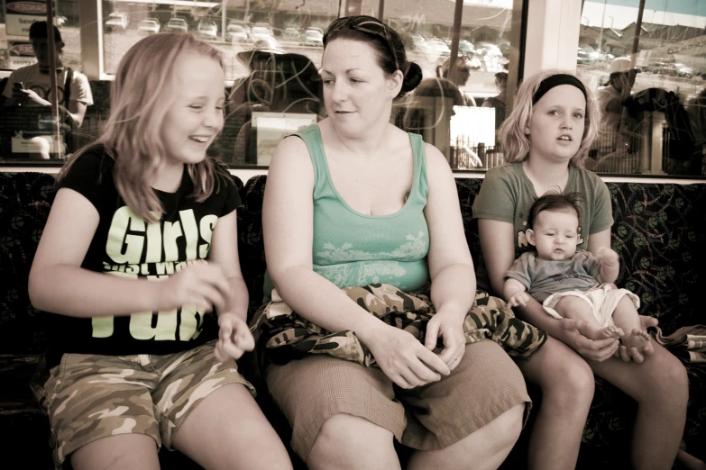 three girls sitting on a bench with a baby