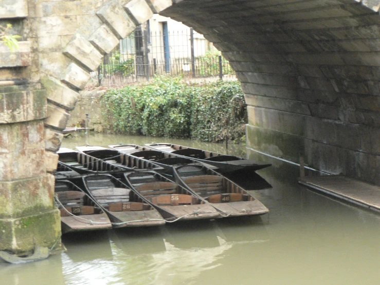 some small boats sitting in the water under an overpass