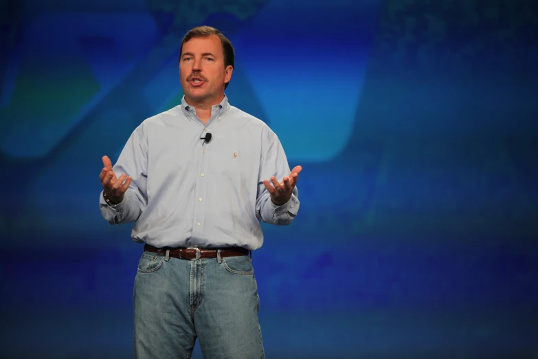 a man in a blue shirt standing and speaking