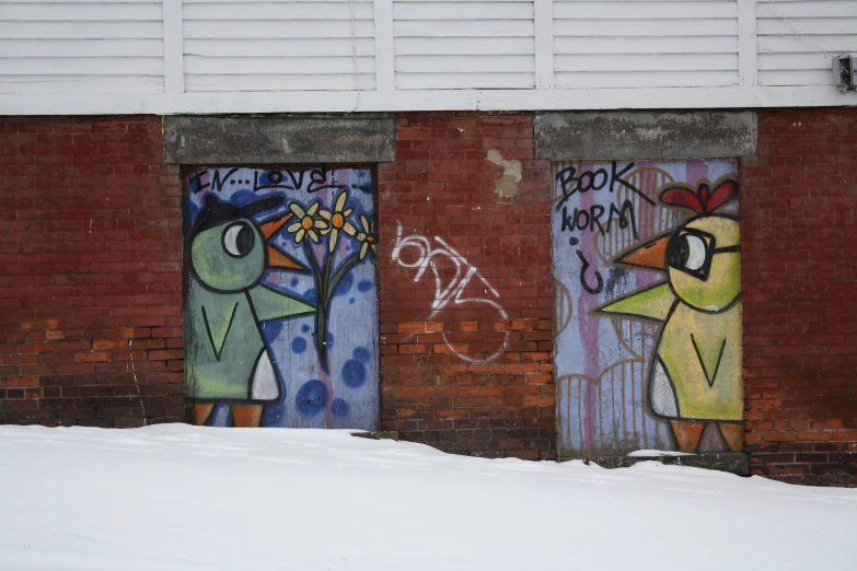 two doors in the snow, one of them is painted with birds