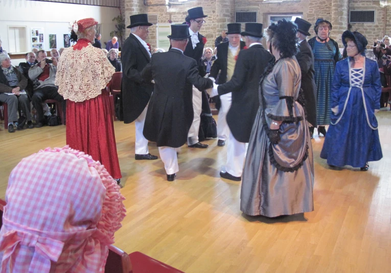 some people are dancing and wearing fancy dress in front of an audience