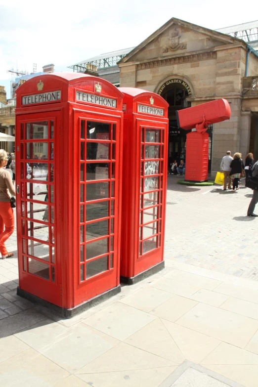 a group of red telephone booths sitting on top of a sidewalk