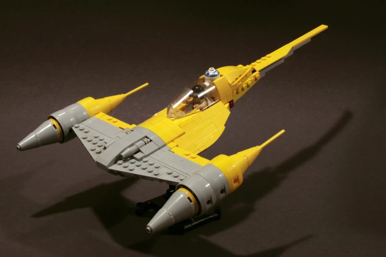 the yellow and silver model airplane is on a black surface