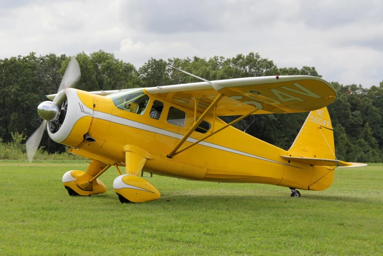 a small yellow and white biplane sitting on grass