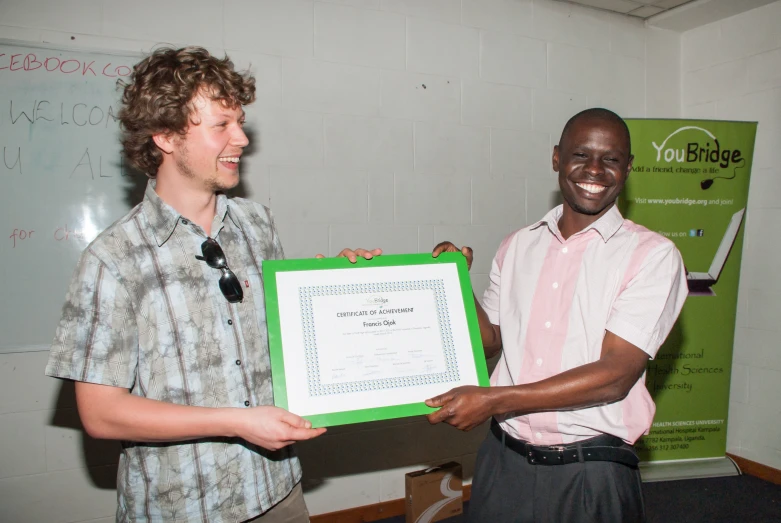 two men in a classroom holding an award