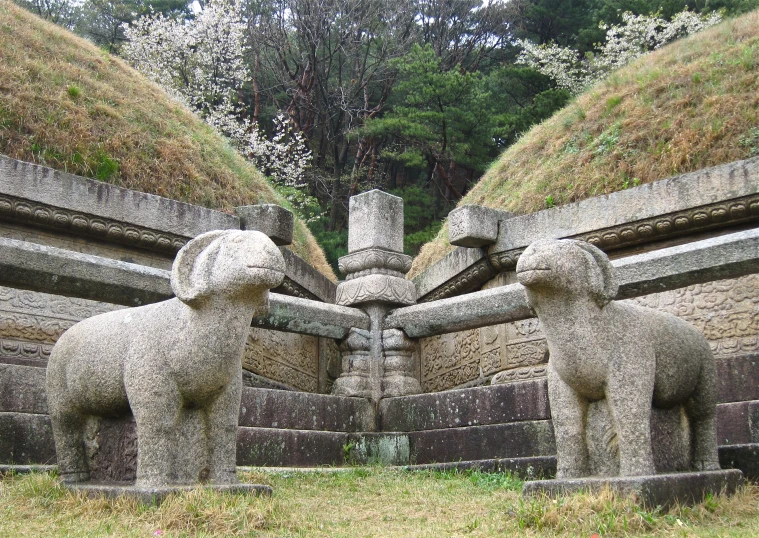 two statues of elephants made out of rock in an open field