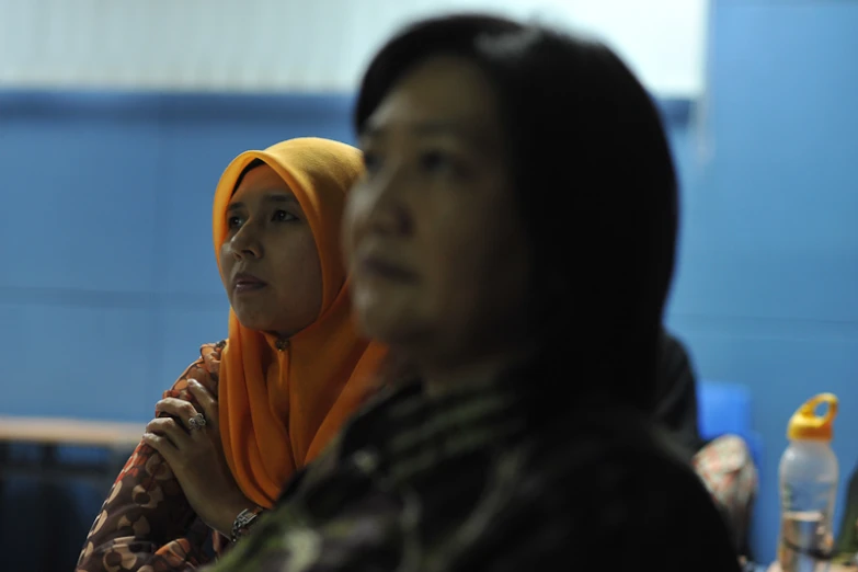 a man standing next to a woman in an orange headscarf