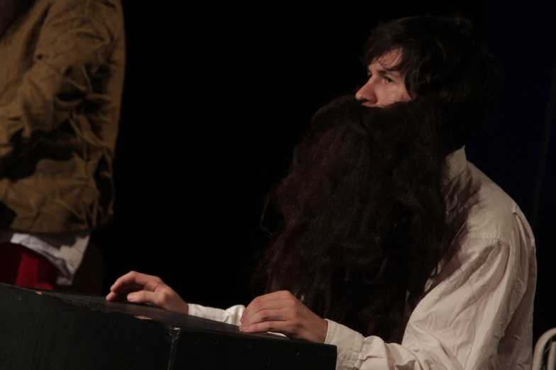 man with long black hair and beard looking at computer screen