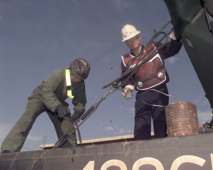 two men in safety gear working on a roof