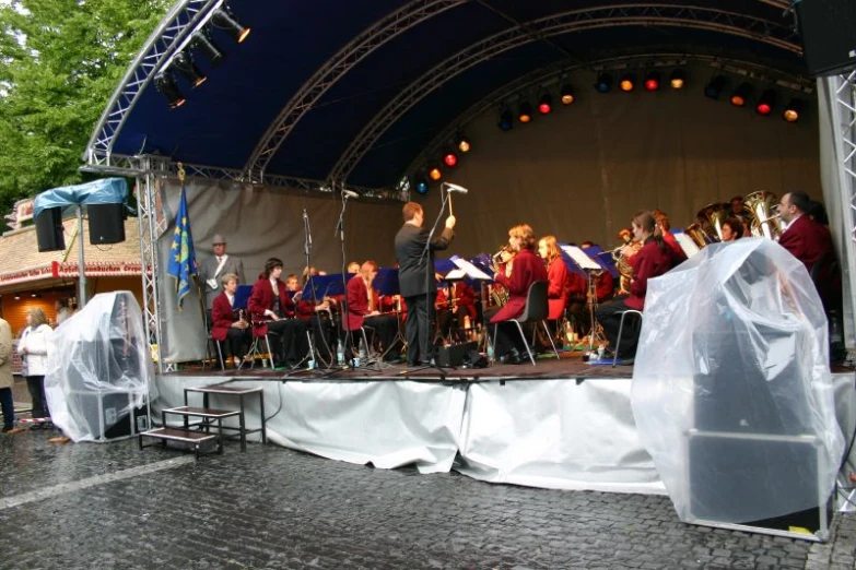 a large group of people on stage under a blue umbrella