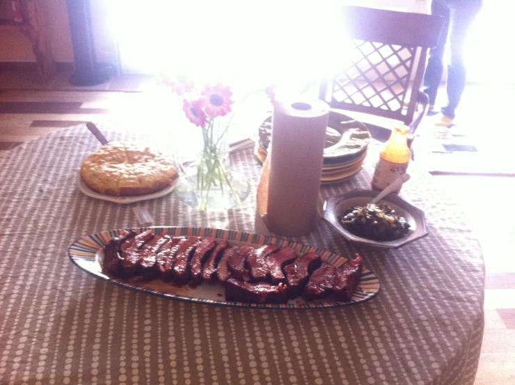 a table has a tray and a plate of meat on it