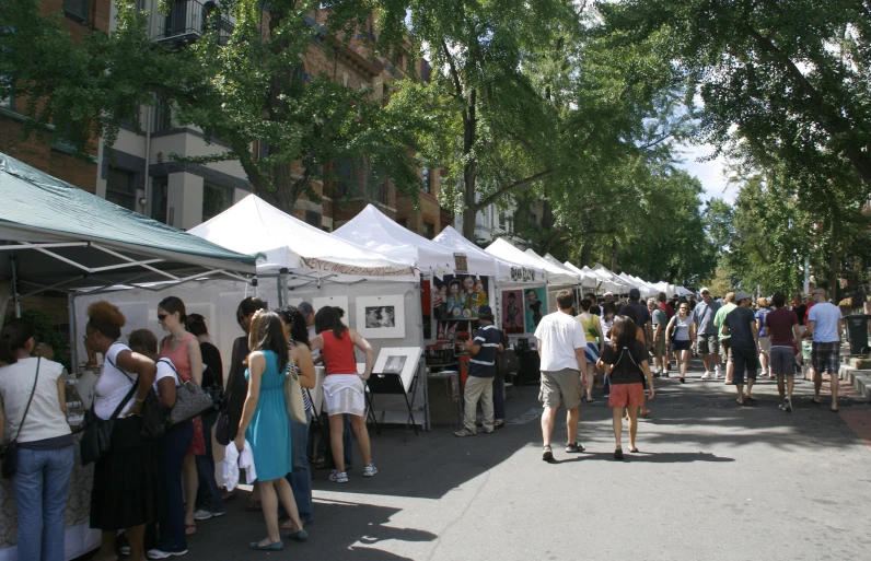 several people walking around tents in a street