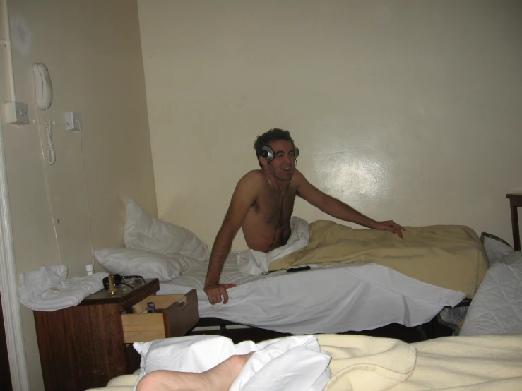 man with  sitting on bed using a cellphone