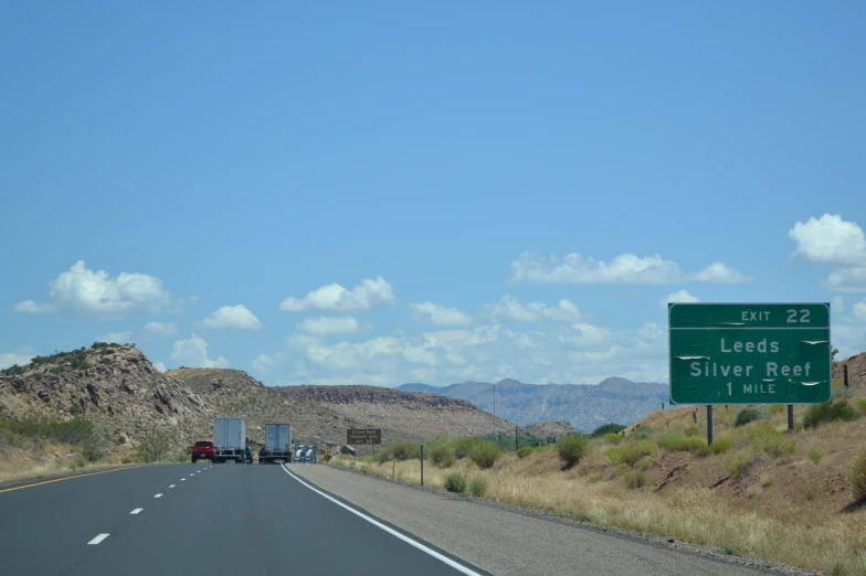 a highway sign next to a freeway with mountains behind it